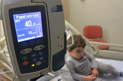 Infusion pump in sharp focus with Pudding on hospital bed behind.
