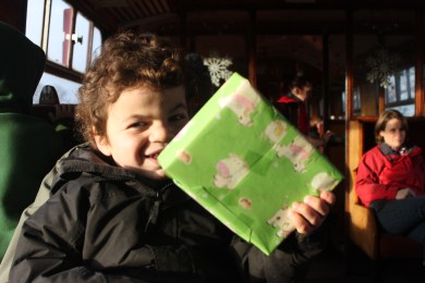 Pudding holding a wrapped present and smiling.