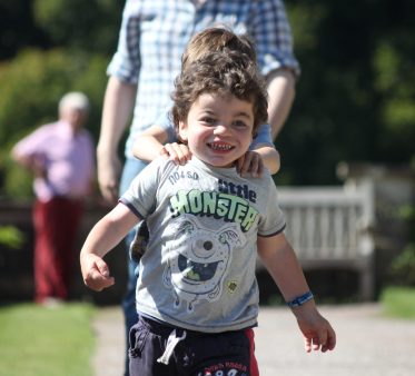 Pudding running towards camera. His big brother is behind him with hands on his shoulders.