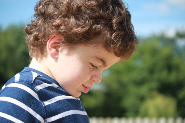 Smiling Pudding in profile with blurred greenery in the background.