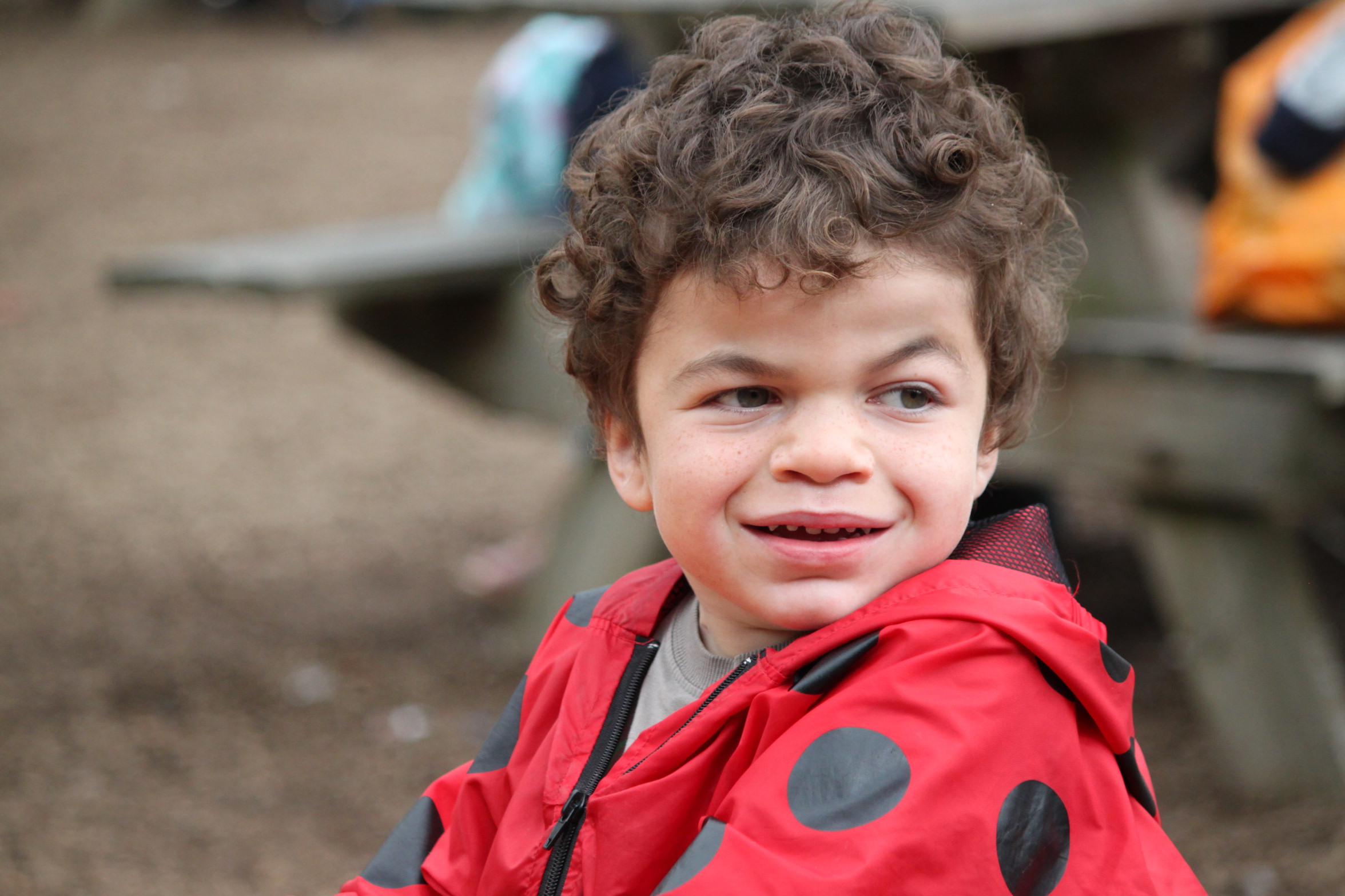 Pudding on a see-saw in a bright red ladybird-design coat.