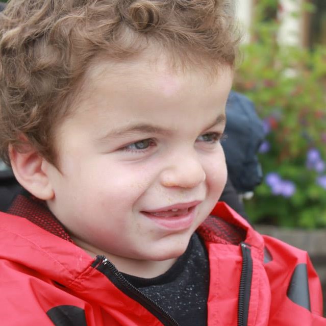 Pudding smiling in a red ladybird jacket.